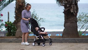 Full length of young woman looking into baby carriage in park stock footage Full length of young woman looking into baby carriage in park stock footage