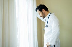 Fundersam stilig medicinsk doktor som ser ut ur medicinskt kontor arkivbilder Fundersam stilig medicinsk doktor som ser ut ur medicinskt kontor arkivbilder