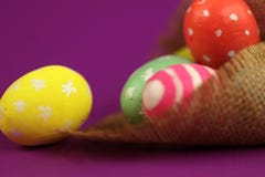 Fundo de Easter Ovos pintados verdes, vermelhos e amarelos feitos a mão na serapilheira no fundo roxo com bokeh foto de stock Fundo de Easter Ovos pintados verdes, vermelhos e amarelos feitos a mão na serapilheira no fundo roxo com bokeh foto de stock