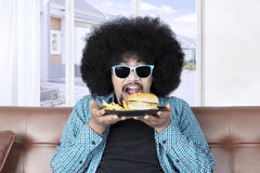 Funky Afro man holds cheeseburger Stock Images Funky Afro man holds cheeseburger Stock Images