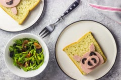 Funny animal sandwich for kids shaped cute pig with boiled sausage and olives. On white plate on grey background, food art idea. Top view stock photos Funny animal sandwich for kids shaped cute pig with boiled sausage and olives. On white plate on grey background, food art idea. Top view stock photos