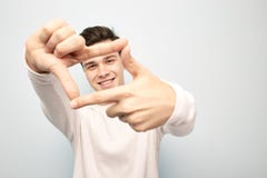 Funny dark-haired guy dressed in a white long sleeve t-shirt stands and keeps his hands in front of him making with stock photos Funny dark-haired guy dressed in a white long sleeve t-shirt stands and keeps his hands in front of him making with stock photos