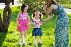 Funny girls walking on the lawn with her mother. Sisters play together with mom. maternal care. happy family stock photo Funny girls walking on the lawn with her mother. Sisters play together with mom. maternal care. happy family stock photo