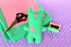 Funny green felt Teddy bear, handmade children toy. Scissors, threads, needles - sewing set stock photos Funny green felt Teddy bear, handmade children toy. Scissors, threads, needles - sewing set stock photos