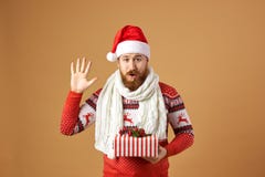 Funny red-haired man with beard dressed in a red and white sweater with deer, white knitted scarf and a hat of Santa royalty free stock image Funny red-haired man with beard dressed in a red and white sweater with deer, white knitted scarf and a hat of Santa royalty free stock image