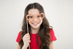 Funny small girl holding glasses photo booth props on stick. Cute kid with fancy party props. Party decorations supplier