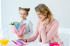 fuoco selettivo della madre felice che esamina la cartolina e la figlia di saluto con il mazzo dei fiori che stanno vicino vicino fotografie stock libere da diritti fuoco selettivo della madre felice che esamina la cartolina e la figlia di saluto con il mazzo dei fiori che stanno vicino vicino fotografie stock libere da diritti
