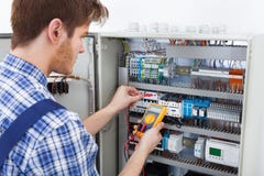 Fusebox d'esame del tecnico con il tester di resistenza di isolamento fotografia stock libera da diritti Fusebox d'esame del tecnico con il tester di resistenza di isolamento fotografia stock libera da diritti