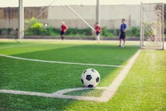 Fußball auf grünem künstlichem Rasen an der Ecke des Fußballplatzes mit undeutlichem Spielerhintergrund lizenzfreies stockbild Fußball auf grünem künstlichem Rasen an der Ecke des Fußballplatzes mit undeutlichem Spielerhintergrund lizenzfreies stockbild