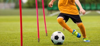 Fußball-Spieler mit Fußball-laufendem Slalom um Trainings-Stöcke Fußball-Geschwindigkeits-Training lizenzfreies stockfoto Fußball-Spieler mit Fußball-laufendem Slalom um Trainings-Stöcke Fußball-Geschwindigkeits-Training lizenzfreies stockfoto
