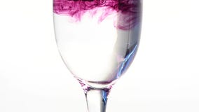 Färben Sie die Tinte, die in Glas Wasser auf weißem Hintergrund fließt stock video Färben Sie die Tinte, die in Glas Wasser auf weißem Hintergrund fließt stock video