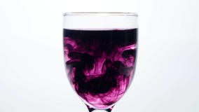 Färben Sie die Tinte, die in Glas Wasser auf weißem Hintergrund fließt stock footage Färben Sie die Tinte, die in Glas Wasser auf weißem Hintergrund fließt stock footage
