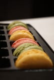 Färgrika macrons (typisk franskt mellanmål) i det svarta plast- magasinet arkivfoton Färgrika macrons (typisk franskt mellanmål) i det svarta plast- magasinet arkivfoton