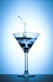Färgstänk för coctailmartini exponeringsglas på vit och blå lutningbakgrund royaltyfria bilder Färgstänk för coctailmartini exponeringsglas på vit och blå lutningbakgrund royaltyfria bilder