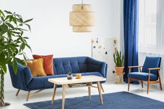 Fåtölj och soffa i blå och orange vardagsruminre med lampan ovanför trätabellen Verkligt foto royaltyfria bilder Fåtölj och soffa i blå och orange vardagsruminre med lampan ovanför trätabellen Verkligt foto royaltyfria bilder