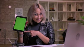 A fêmea loura caucasiano bonito está mostrando a tela verde quando se sentar interno no desktop no computador, demonstrações gost ilustração do vetor A fêmea loura caucasiano bonito está mostrando a tela verde quando se sentar interno no desktop no computador, demonstrações gost ilustração do vetor