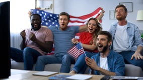 Fósforo de observação dos fãs americanos multirraciais na tevê em casa, comemorando o objetivo da equipe imagens de stock Fósforo de observação dos fãs americanos multirraciais na tevê em casa, comemorando o objetivo da equipe imagens de stock