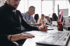 F?r kontorsstil f?r grabben den ikl?dda tillf?lliga kl?derna fungerar med dokument som sitter p? skrivbordet med datoren bredvid fotografering för bildbyråer F?r kontorsstil f?r grabben den ikl?dda tillf?lliga kl?derna fungerar med dokument som sitter p? skrivbordet med datoren bredvid fotografering för bildbyråer
