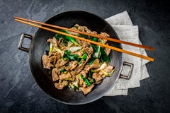 För mongoliannötkött för traditionell kines småfisk för uppståndelse i kinesiskt gjutjärn wokar med matlagningpinnar, sten kritis arkivfoton För mongoliannötkött för traditionell kines småfisk för uppståndelse i kinesiskt gjutjärn wokar med matlagningpinnar, sten kritis arkivfoton
