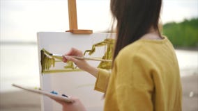 För målareteckning för ung kvinna bild för landskap för vattenfärg på staffli stock video För målareteckning för ung kvinna bild för landskap för vattenfärg på staffli stock video