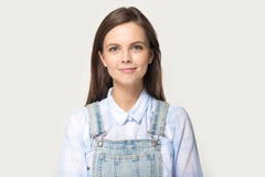 För skjortagrov bomullstvill för kvinna som bärande overall poserar på grå studiobakgrund arkivfoto För skjortagrov bomullstvill för kvinna som bärande overall poserar på grå studiobakgrund arkivfoto