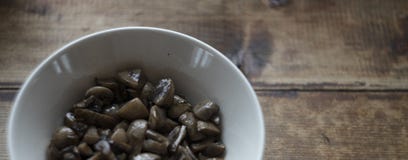 Förberedda klippta champinjoner i den vita plattan på mörk grov träbakgrund, foto för bystilmat royaltyfria foton Förberedda klippta champinjoner i den vita plattan på mörk grov träbakgrund, foto för bystilmat royaltyfria foton