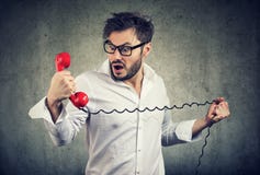 Förbittrad chockad man som ser i misstro på telefontelefonluren royaltyfri fotografi Förbittrad chockad man som ser i misstro på telefontelefonluren royaltyfri fotografi