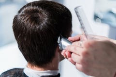 Förlagen klipper hår av män i frisersalongen, frisör gör frisyren för en ung man fotografering för bildbyråer Förlagen klipper hår av män i frisersalongen, frisör gör frisyren för en ung man fotografering för bildbyråer