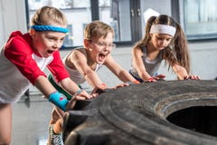 Förtjusande ungar i sportswearutbildning med gummihjulet på konditionstudion fotografering för bildbyråer Förtjusande ungar i sportswearutbildning med gummihjulet på konditionstudion fotografering för bildbyråer