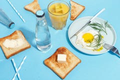 Förvanskade ägg, bredde smör på rostade bröd och drinkar på en blå tabell Bästa sikt för frukost fotografering för bildbyråer Förvanskade ägg, bredde smör på rostade bröd och drinkar på en blå tabell Bästa sikt för frukost fotografering för bildbyråer