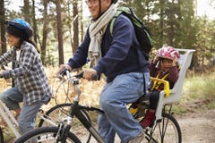 Föräldrar som cyklar i en skog med litet barndottern, slut upp royaltyfri fotografi Föräldrar som cyklar i en skog med litet barndottern, slut upp royaltyfri fotografi