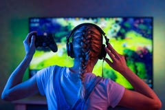 Gamer или девушка ленты дома в темной комнате с gamepad играя с друзьями на сетях в видеоиграх Молодой человек стоковое изображение rf Gamer или девушка ленты дома в темной комнате с gamepad играя с друзьями на сетях в видеоиграх Молодой человек стоковое изображение rf