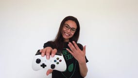 Gamerflicka som inviterar för lek med kontrollanten på hennes hand Vit bakgrund lager videofilmer Gamerflicka som inviterar för lek med kontrollanten på hennes hand Vit bakgrund lager videofilmer