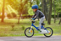 Gar?on heureux d'enfant de 5 ans ayant le parc d'amusement au printemps avec une bicyclette le beau jour d'automne Casque de port photos stock Gar?on heureux d'enfant de 5 ans ayant le parc d'amusement au printemps avec une bicyclette le beau jour d'automne Casque de port photos stock
