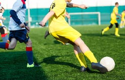 Gar?ons d'?quipes de football dans le football blanc jaune de jeu de v?tements de sport sur le champ vert qualifications de ruiss photo libre de droits Gar?ons d'?quipes de football dans le football blanc jaune de jeu de v?tements de sport sur le champ vert qualifications de ruiss photo libre de droits