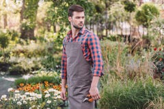 Gardener in apron holding pruning shears in hand while standing in garden royalty free stock photography Gardener in apron holding pruning shears in hand while standing in garden royalty free stock photography