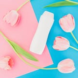 Garrafa do champô e flores das tulipas no fundo cor-de-rosa e azul Configuração lisa, vista superior Conceito da beleza fotografia de stock Garrafa do champô e flores das tulipas no fundo cor-de-rosa e azul Configuração lisa, vista superior Conceito da beleza fotografia de stock