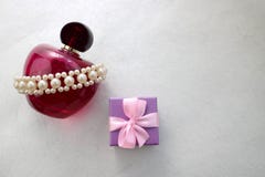 Garrafa transparente de vidro bonita cor-de-rosa do perfume fêmea decorada com as pérolas preciosas brancas e caixa de presente e Fotografia de Stock Garrafa transparente de vidro bonita cor-de-rosa do perfume fêmea decorada com as pérolas preciosas brancas e caixa de presente e Fotografia de Stock
