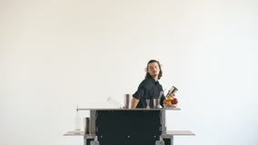 Garrafas do homem do barman de Professinal e cocktail de mnanipulação da agitação na tabela móvel da barra no fundo branco filme Garrafas do homem do barman de Professinal e cocktail de mnanipulação da agitação na tabela móvel da barra no fundo branco filme