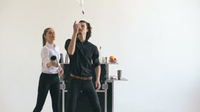 Garrafas profissionais do homem e da mulher do barman e cocktail de mnanipulação da agitação na tabela móvel da barra no estúdio video estoque Garrafas profissionais do homem e da mulher do barman e cocktail de mnanipulação da agitação na tabela móvel da barra no estúdio video estoque