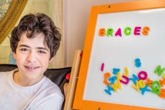 Garçon avec des accolades et des lettres magnétiques Image stock Garçon avec des accolades et des lettres magnétiques Image stock