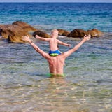 Garçon d'enfant en bas âge sur les épaules du père à la plage photographie stock Garçon d'enfant en bas âge sur les épaules du père à la plage photographie stock