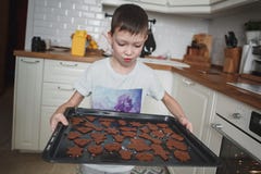 Garçon de 8 regards étonnés et heureux d'ans sur le plateau de cuisine des gâteaux aux pépites de chocolat photos stock Garçon de 8 regards étonnés et heureux d'ans sur le plateau de cuisine des gâteaux aux pépites de chocolat photos stock