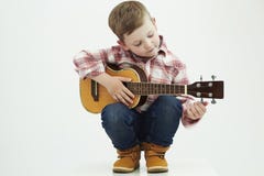 Garçon drôle d'enfant avec la guitare garçon de la campagne jouant la musique image stock Garçon drôle d'enfant avec la guitare garçon de la campagne jouant la musique image stock