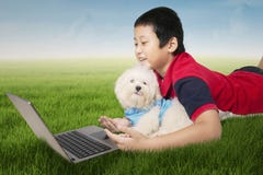 Garçon et chien utilisant l'ordinateur portable au champ Photos libres de droits