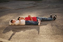 Garçon et fille se trouvant sur l'asphalte Photographie stock libre de droits Garçon et fille se trouvant sur l'asphalte Photographie stock libre de droits