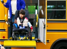 Garçon handicapé sur le levage de fauteuil roulant de bus photographie stock libre de droits Garçon handicapé sur le levage de fauteuil roulant de bus photographie stock libre de droits