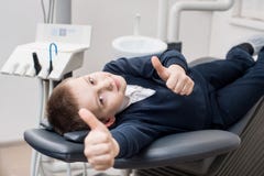 Garçon patient heureux montrant des pouces au bureau dentaire Concept de médecine, de stomatologie et de soins de santé images stock Garçon patient heureux montrant des pouces au bureau dentaire Concept de médecine, de stomatologie et de soins de santé images stock