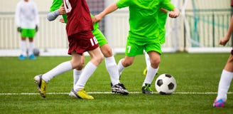 Garçons donnant un coup de pied la partie de football du football Jeunes footballeurs courants photo stock Garçons donnant un coup de pied la partie de football du football Jeunes footballeurs courants photo stock