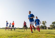 Garçons jouant le jeu de football du football sur le champ de sports image stock Garçons jouant le jeu de football du football sur le champ de sports image stock